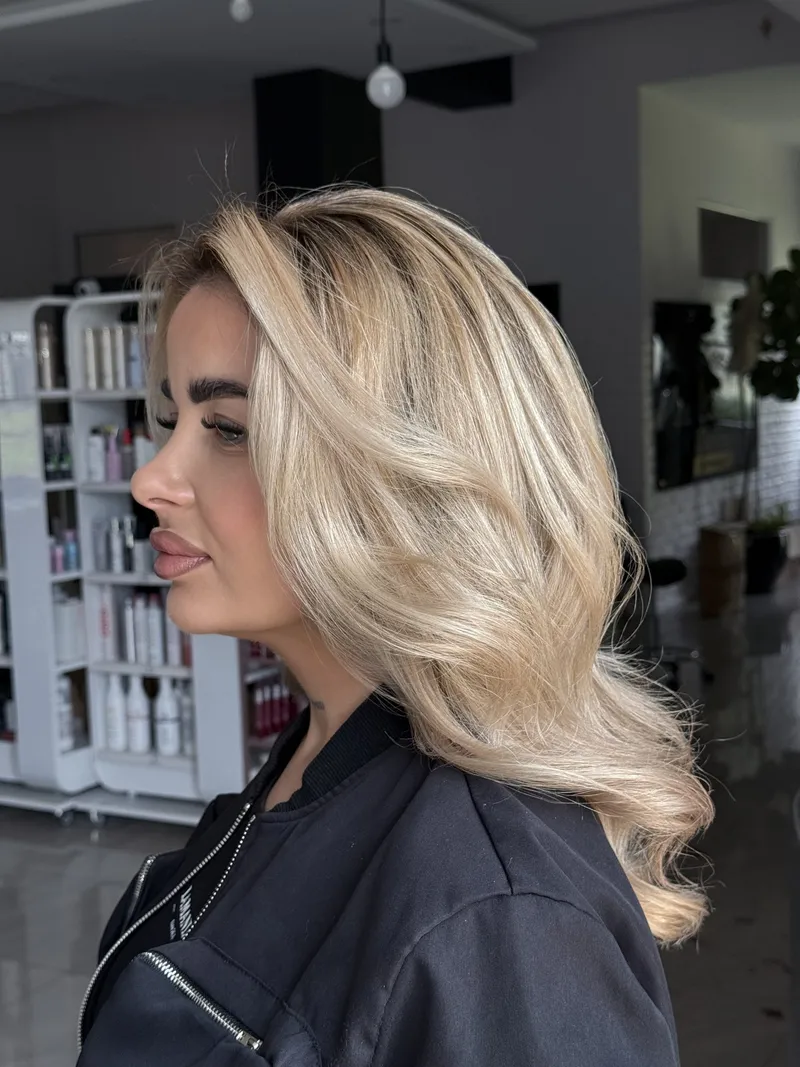 Klientka z jasnymi falami blond, ujęcie z profilu w salonie